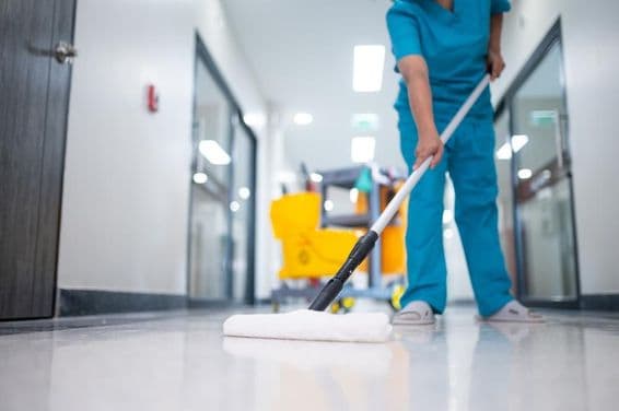 Reinigungskraft wischt den Flur.