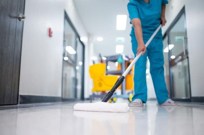 Reinigungskraft wischt den Flur.