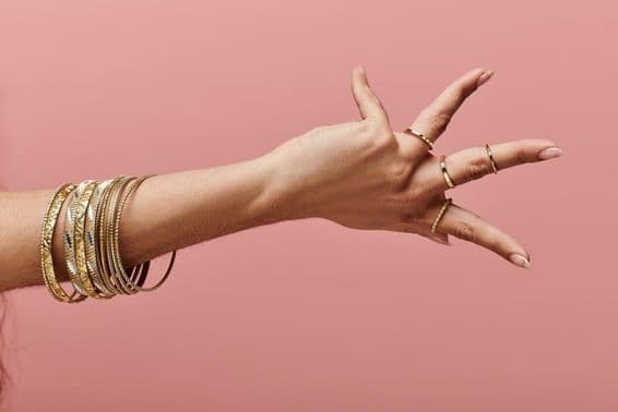 Indische Frau posiert elegant mit Goldarmreifen am Handgelenk.