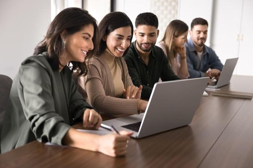 Multinationale junge erwachsene Schüler, die in einem Bildungszentrum an Laptops studieren.