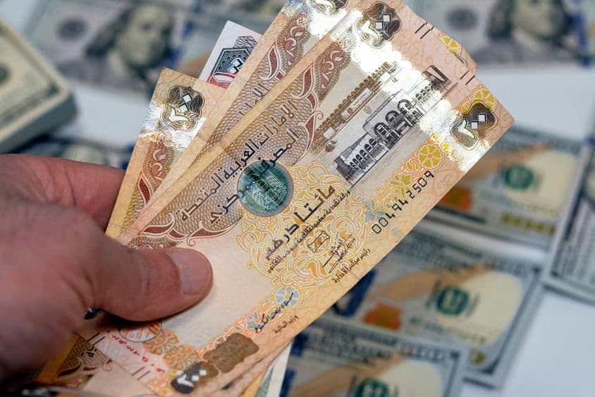 Ein Mann hält ein Bündel mit 200 Dirham-Scheinen der Vereinigten Arabischen Emirate.