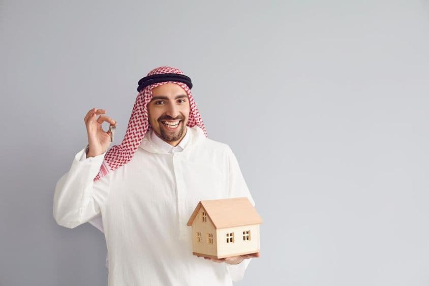 Arabischer Immobilienmakler hält ein Hausmodell.