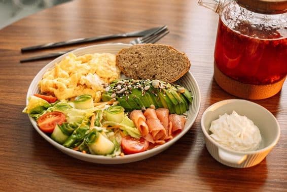 Gesundes Frühstück mit Eiern, Avocado, Gemüse, Salat und Himbeertee.