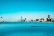 Blick auf die Strandpromenade von Abu Dhabi mit einem vorbeifahrenden Fischerboot.