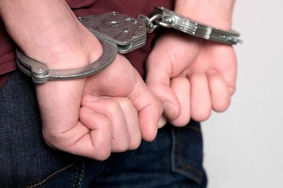 Ein verhafteter Krimineller in Handschellen aufgrund von Verbrechen.
