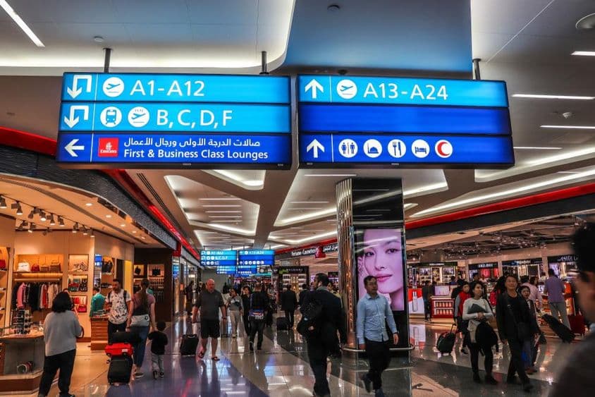 Passagiere gehen auf die Abflugterminals am Dubai International Airport (DXB) zu.