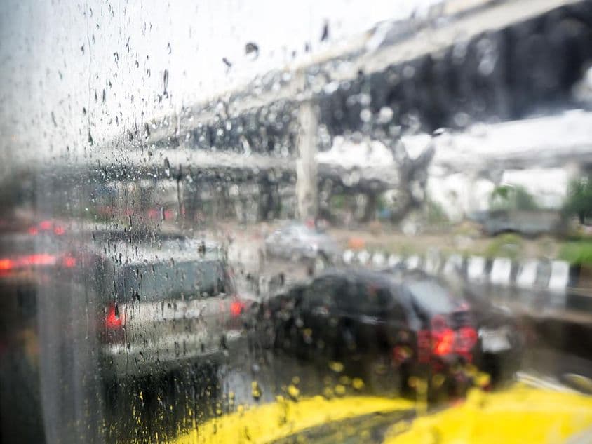 Verkehr an einem regnerischen Tag mit Regentropfen auf der Autoscheibe.
