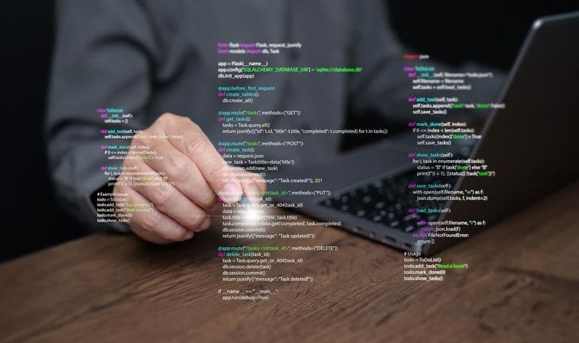 Hände eines Programmierers auf einem Laptop mit Code