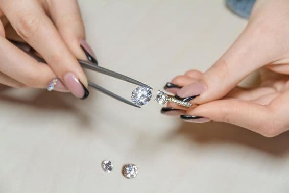 Hände einer Juwelierin, die einen Edelstein hält.