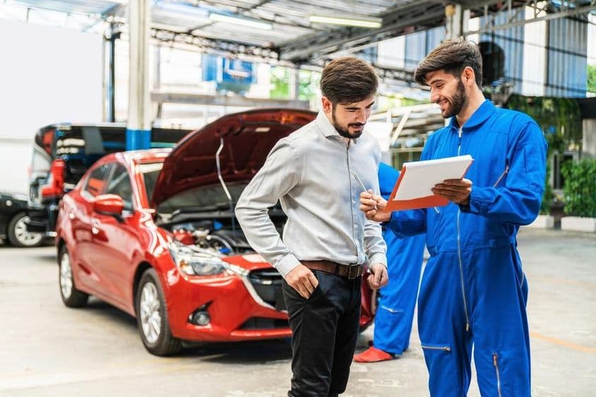 Mechaniker zeigt einem Kunden die Checkliste der Fahrzeuginspektion.