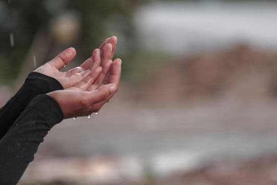 Eine Frau betet mit Händen um Regen.