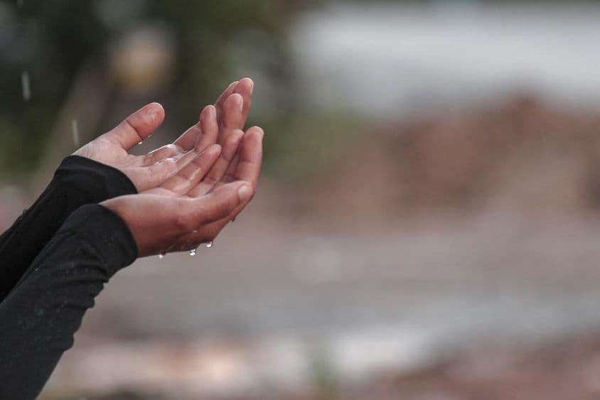 Eine Frau betet mit Händen um Regen.