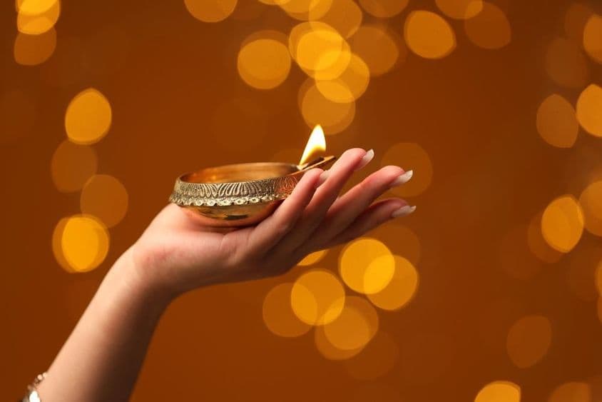 Frau hält eine angezündete Diwali-Lampe
