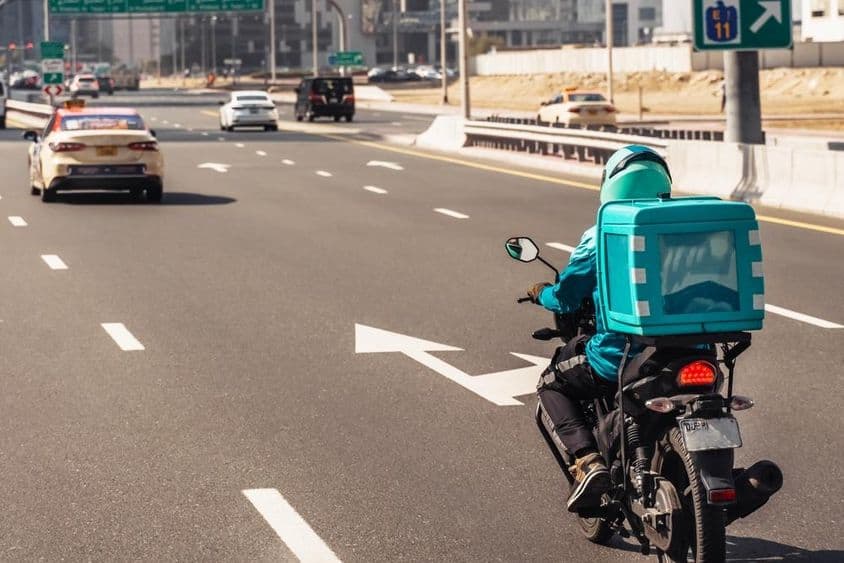 Dubai, Mann auf Motorrad für Online-Essenslieferung.