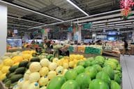 Gestapelte grüne und gelbe Melonen zum Verkauf für Verbraucher in einem Supermarkt in einem Einkaufszentrum in Dubai.