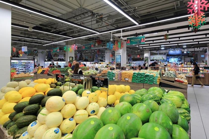 Gestapelte grüne und gelbe Melonen zum Verkauf für Verbraucher in einem Supermarkt in einem Einkaufszentrum in Dubai.