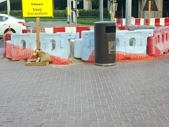 Die Straßenausbesserung ist von Plastikbarrieren und einem orangefarbenen Sicherheitsnetz umgeben.