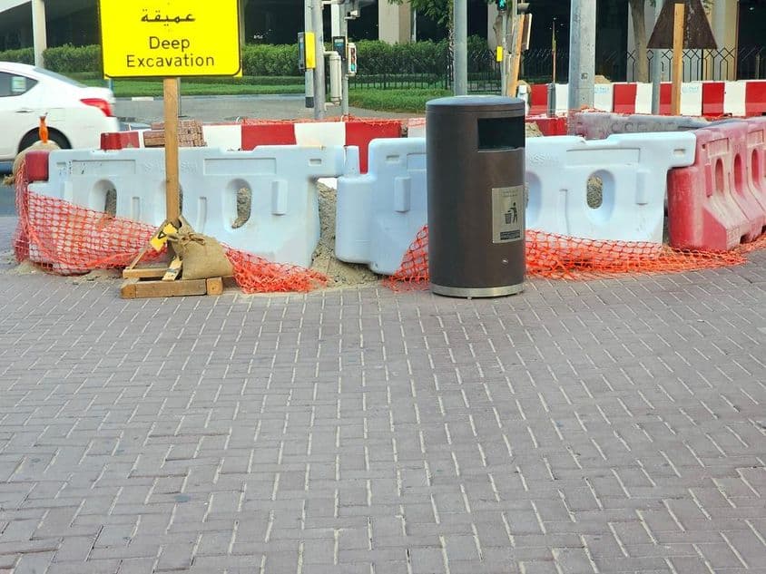 Die Straßenausbesserung ist von Plastikbarrieren und einem orangefarbenen Sicherheitsnetz umgeben.
