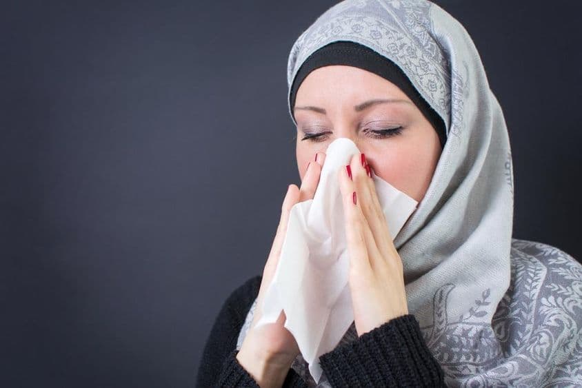 Eine schöne muslimische Frau mit Erkältung und laufender Nase.