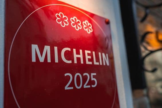 Eine rote, mit drei Michelin-Sternen 2025 versehene Plakette an einer hellen Wand.