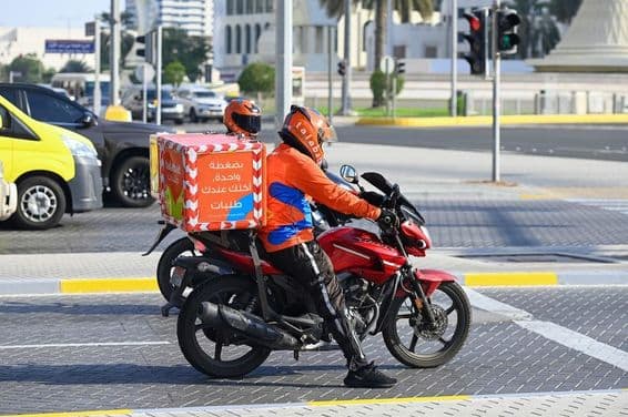 Talabat-Online-Lebensmittellieferdienst-Kuriere auf einer Straße in Abu Dhabi.