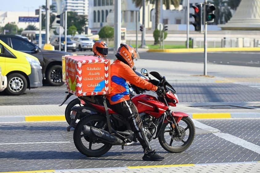 Talabat-Online-Lebensmittellieferdienst-Kuriere auf einer Straße in Abu Dhabi.