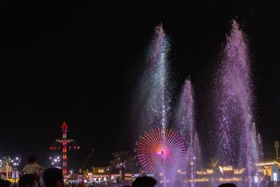 Die lebendige Nachtszene beim Sheikh Zayed Festival mit Wasserfontänen.