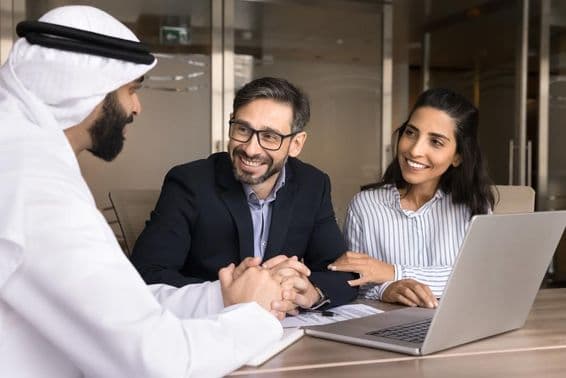 Ein glückliches lateinamerikanisches Paar trifft sich mit einem arabischen Immobilienmakler.