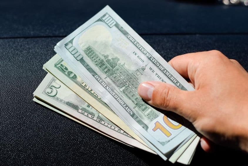 Ein Bündel Dollar in der Hand eines Mannes.