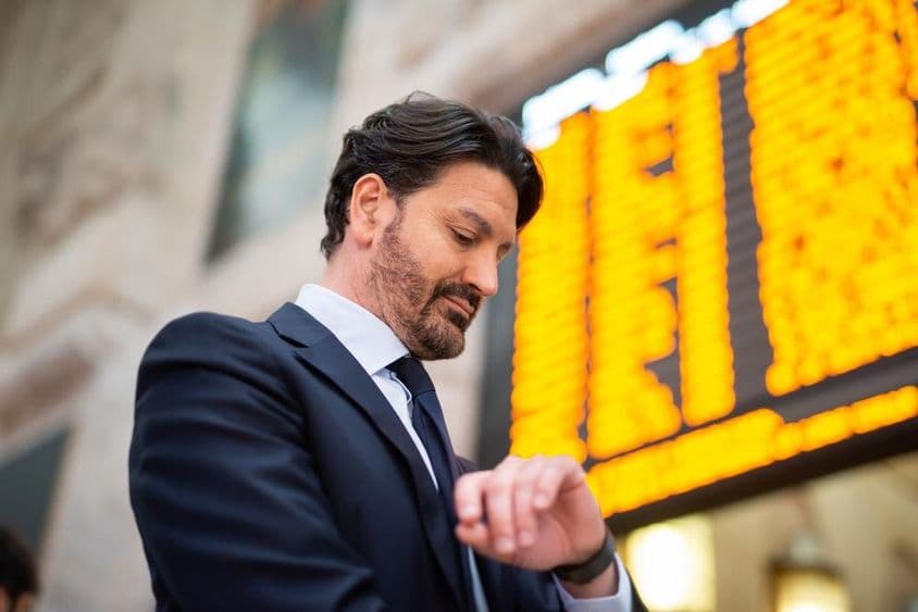 Ein Pendler überprüft die Uhrzeit vor einem Fahrplan.