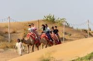 Touristen reiten auf Kamelen in der Wüste.