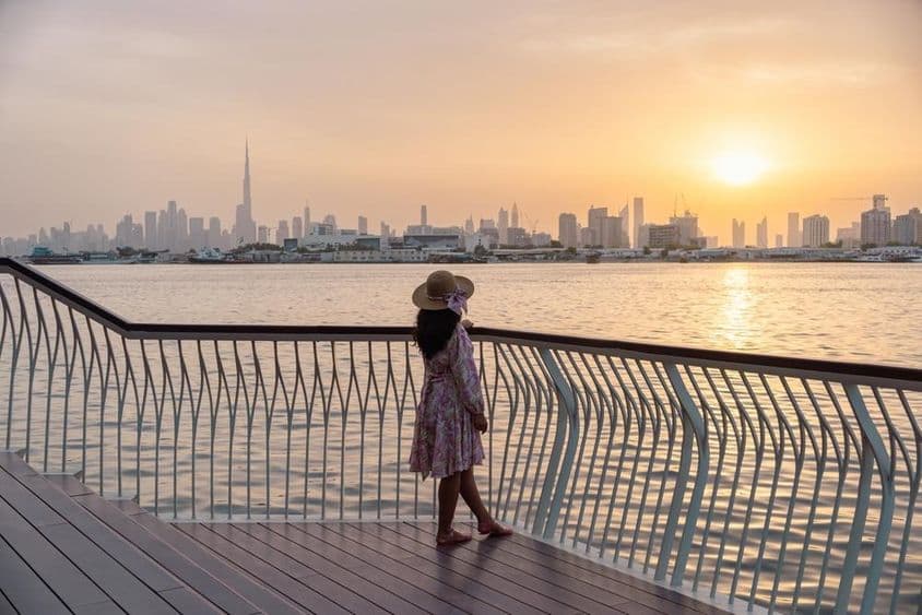 Junge Frau blickt auf Dubais Skyline im Sonnenuntergang.