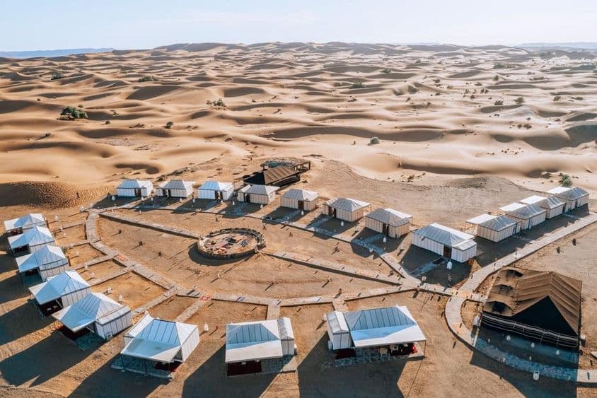 Ein Camp in der Wüste, umgeben von weiten Sanddünen.
