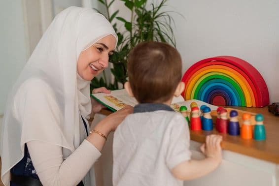 Eine muslimische Lehrerin und ein Kindergartenkind spielen mit bunten Spielzeugen.