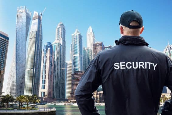 Männlicher Sicherheitsbeamter beobachtet Skyline der Stadt von hinten.