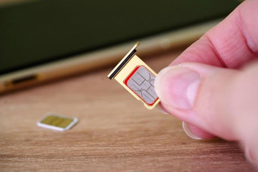 Person, die eine SIM-Karte in die Rückseite eines Mobiltelefons einlegt.