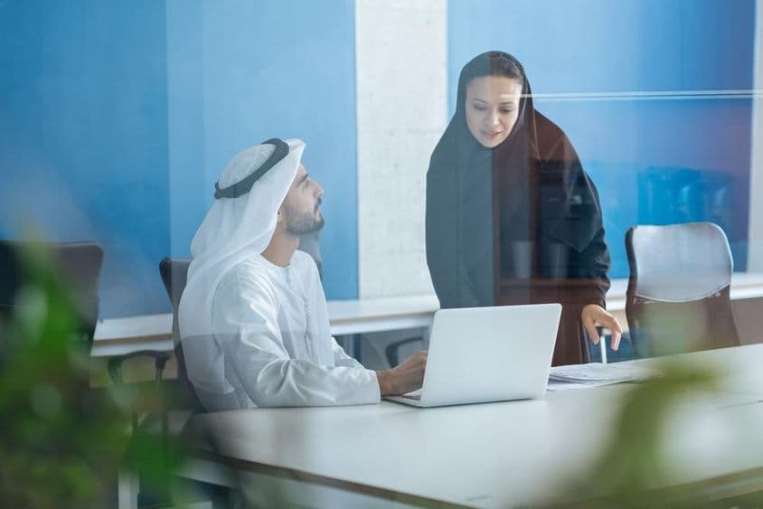 Mann und Frau in traditioneller Kleidung arbeiten in einem Büro in Dubai.