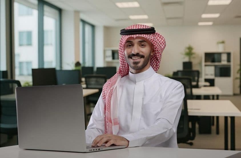 Lächelnder saudisch-arabischer Mann in traditioneller Kleidung bei der Arbeit.