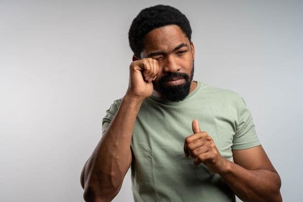 Eine Person reibt sich unwohl die Augen, fühlt sich gereizt und müde.