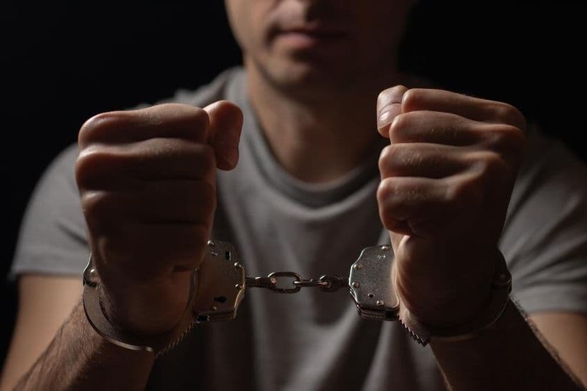 Hände nach vorne gehalten mit Handschellen.