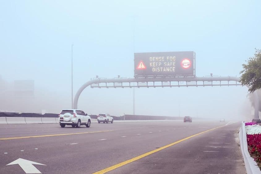 Nebel auf der Straße mit einem Schild 'Abstand halten'.