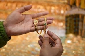 Eine Hand probiert ein luxuriöses Goldarmband in einem Schmuckgeschäft an.