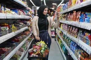 Eine junge Araberin betrachtet Snacks in einem Supermarkt.