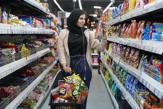 Eine junge Araberin betrachtet Snacks in einem Supermarkt.