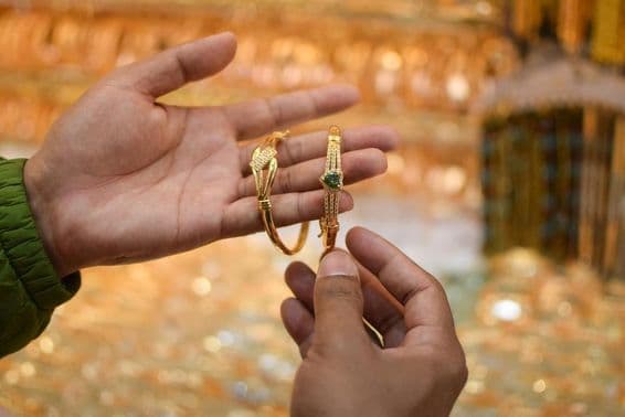 Eine Hand, die ein luxuriöses Goldarmband anprobiert