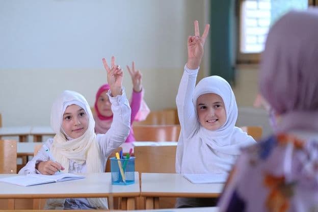 Muslimische Schüler heben die Hand zur Beantwortung von Lehrerfragen.