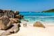 Zwei Reisende gehen am weichen weißen Sandstrand von Anse Cocos Beach auf den Seychellen spazieren.