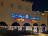 Beleuchtetes Logo von Carrefour-Markt mit arabischem Markennamen