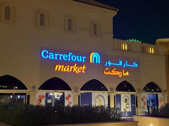 Beleuchtetes Logo von Carrefour-Markt mit arabischem Markennamen