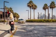 Frau steht auf der Straße und wartet auf ein Taxi.